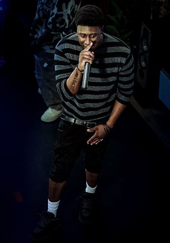 2Plby$ at RRL 2026, in striped sweater performing with mic under dim blue floor light