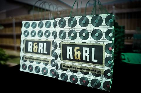 Behind the scenes at RRL 2026, two R&RL gift bags with vinyl record artwork reading Building Our Own Stage