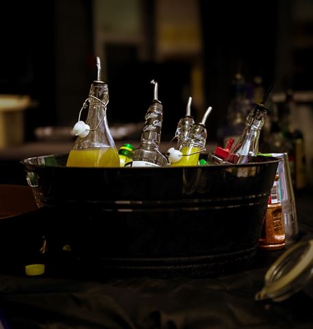 Behind the scenes at RRL 2026, metal tub of swing-top bottles and pour spouts on the dimly lit bar table