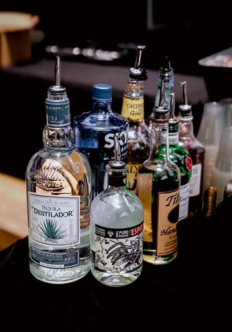 Behind the scenes at RRL 2026, bottles fitted with pour spouts arranged on the dark bar table