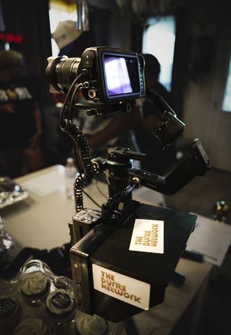 Behind the scenes at RRL 2026, cinema camera on gimbal rig with Durite Network stickers, treats in the foreground
