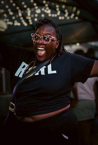 Behind the scenes at RRL 2026, excited guest in leopard-print glasses and black RRL tee under the string lights