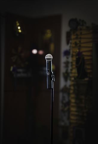 Behind the scenes at RRL 2026, wireless microphone on stand spotlit against the dark room with warm bokeh