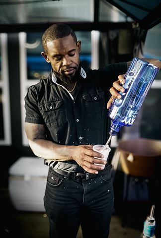 Behind the scenes at RRL 2026, bartender pouring from a large blue bottle at the bar