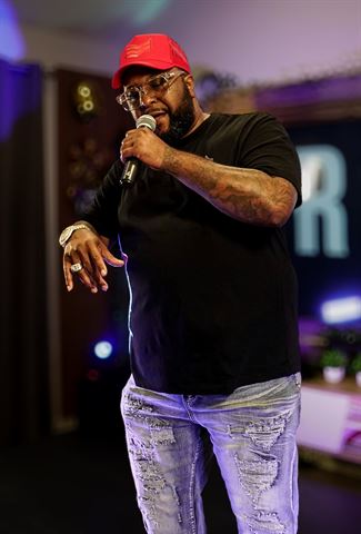 Big Tone P at RRL 2026, in red cap, glasses and distressed jeans singing into the mic in the purple-lit room