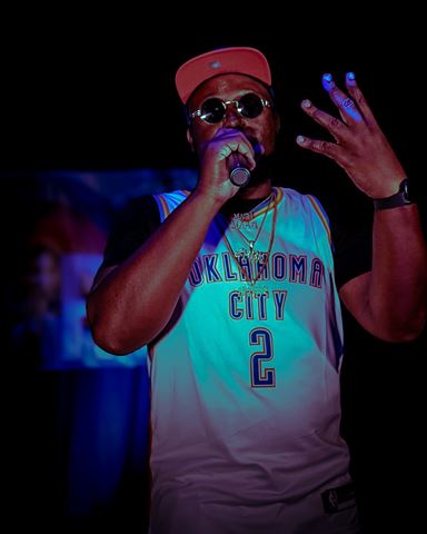 Big Tree #4real at RRL 2026, in red cap, round sunglasses and Oklahoma City jersey rapping under blue-purple light