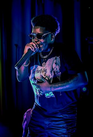 Booga Brim at RRL 2026, in sunglasses, chains and horse-graphic tee performing under purple-blue light