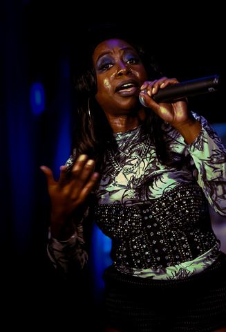 DVine at RRL 2026, singing into the mic with hand extended, green and blue stage light on her face