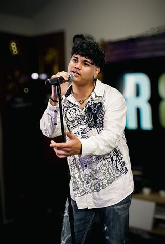 Evver The Thinker at RRL 2026, in white embroidered shirt gesturing while singing into the mic on its stand