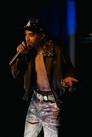 KaliiFreak at RRL 2026, in jeweled cap and leopard-collared jacket rapping into the mic