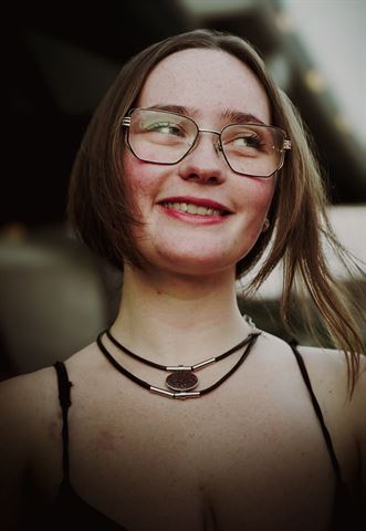 Kameryn Taelyr at RRL 2026, smiling guest with glasses and choker necklaces in soft outdoor light