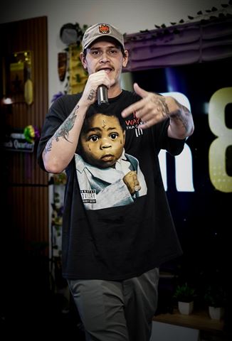 Kocain at RRL 2026, in tan cap and black Lil Wayne tee rapping into handheld mic, gesturing forward
