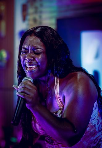 Nuu Era at RRL 2026, singing passionately into handheld mic, eyes closed, bathed in purple and blue light