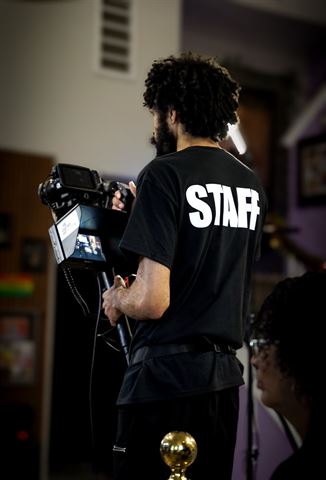 RRL Crew, camera operator in STAFF shirt filming with rigged camera and monitor
