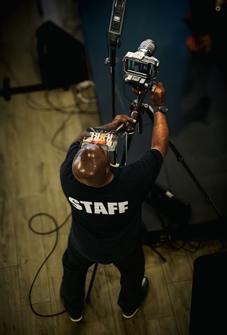 RRL Crew, overhead view of a crew member in a STAFF shirt adjusting the video camera