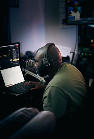 RRL Crew, crew member in headphones at the laptop and audio mixer in the dim control room