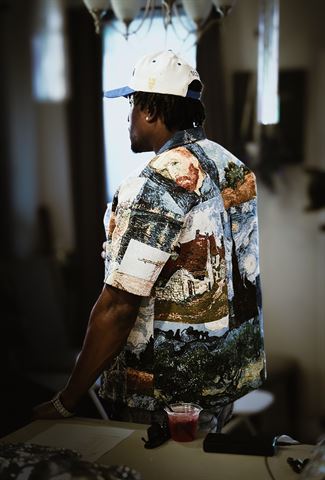 Tay No Tee at RRL 2026, artist from behind in Van Gogh tapestry shirt and cream cap near bright window