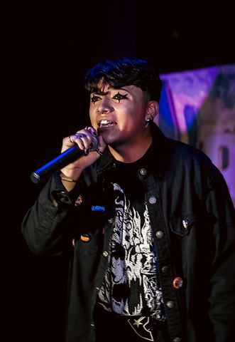 Untitled Flows at RRL 2026, star eye makeup and pinned black jacket, rapping into the mic on the dark stage