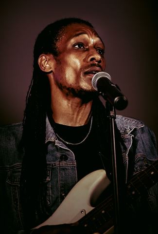 Yadin Kol at RRL 2026, close-up at the mic in denim jacket under warm side light